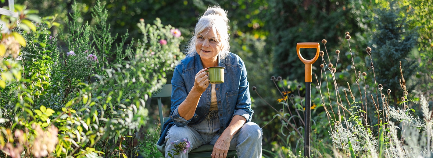 Frau trinkt Kaffee in ihrem autarken Garten