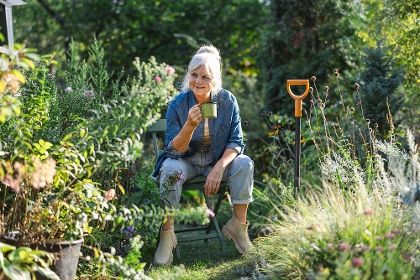 Frau trinkt Kaffee in ihrem autarken Garten