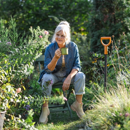 Frau trinkt Kaffee in ihrem autarken Garten