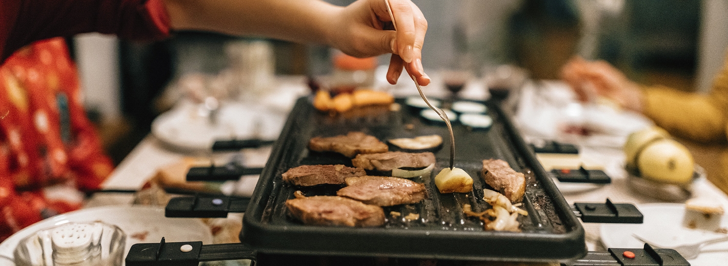 Familie bereiten gemeinsam Raclette an Silvester zu