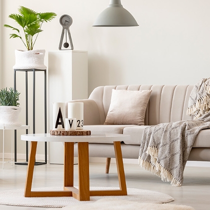 Wohnzimmer in warmen weißen Farbtönen und grauen Akzenten, wie Lampe, Uhr und Hocker