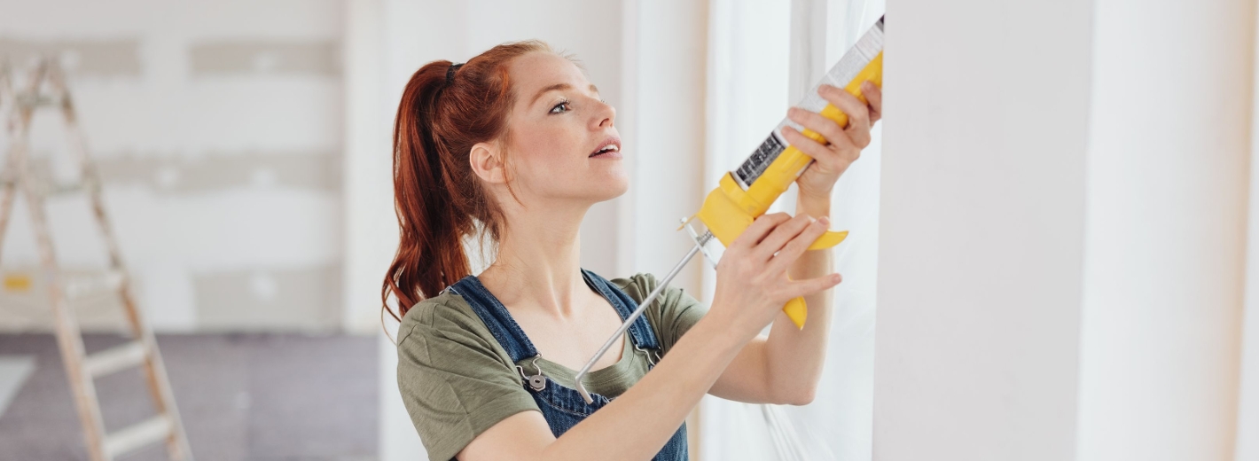 Frau arbeitet an einer Zwischenwand mit Silikon