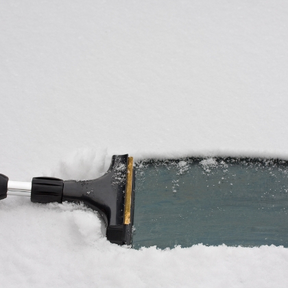 Eiskratzer befreit Auto von Schnee.