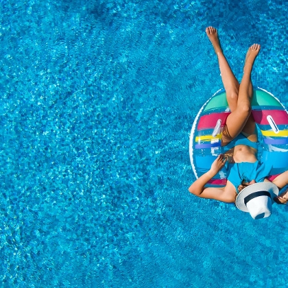 Aus der Vogelperspektive: Frau liegt auf Schwimmring im Pool