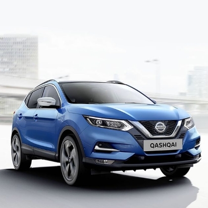 Ein blaues Auto des Modells Nissan QASHQAI fährt auf der Autobahn durch eine Großstadt. Im Hintergrund erkennt man eine Brücke und Hochhäuser.
