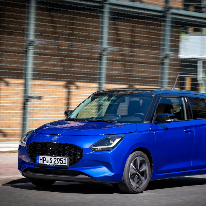 Blauer Suzuki Swift geparkt vor einem städtischen Basketballplatz.