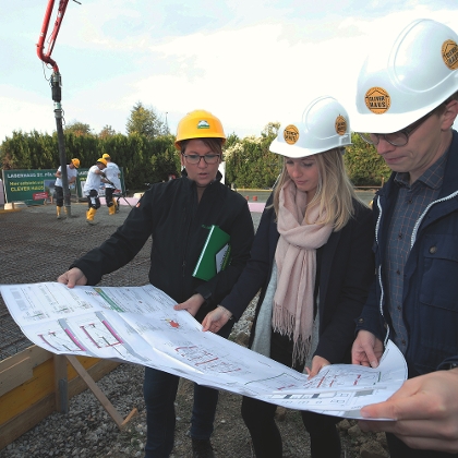 Lagerhaus Planerin bespricht mit Bauherren Einreichplan auf der Baustelle