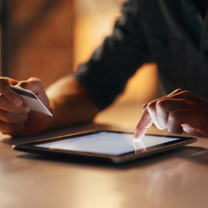 Person führt eine Zahlung mittels Kredit- oder Bankomatkarte über ein Tablet durch
